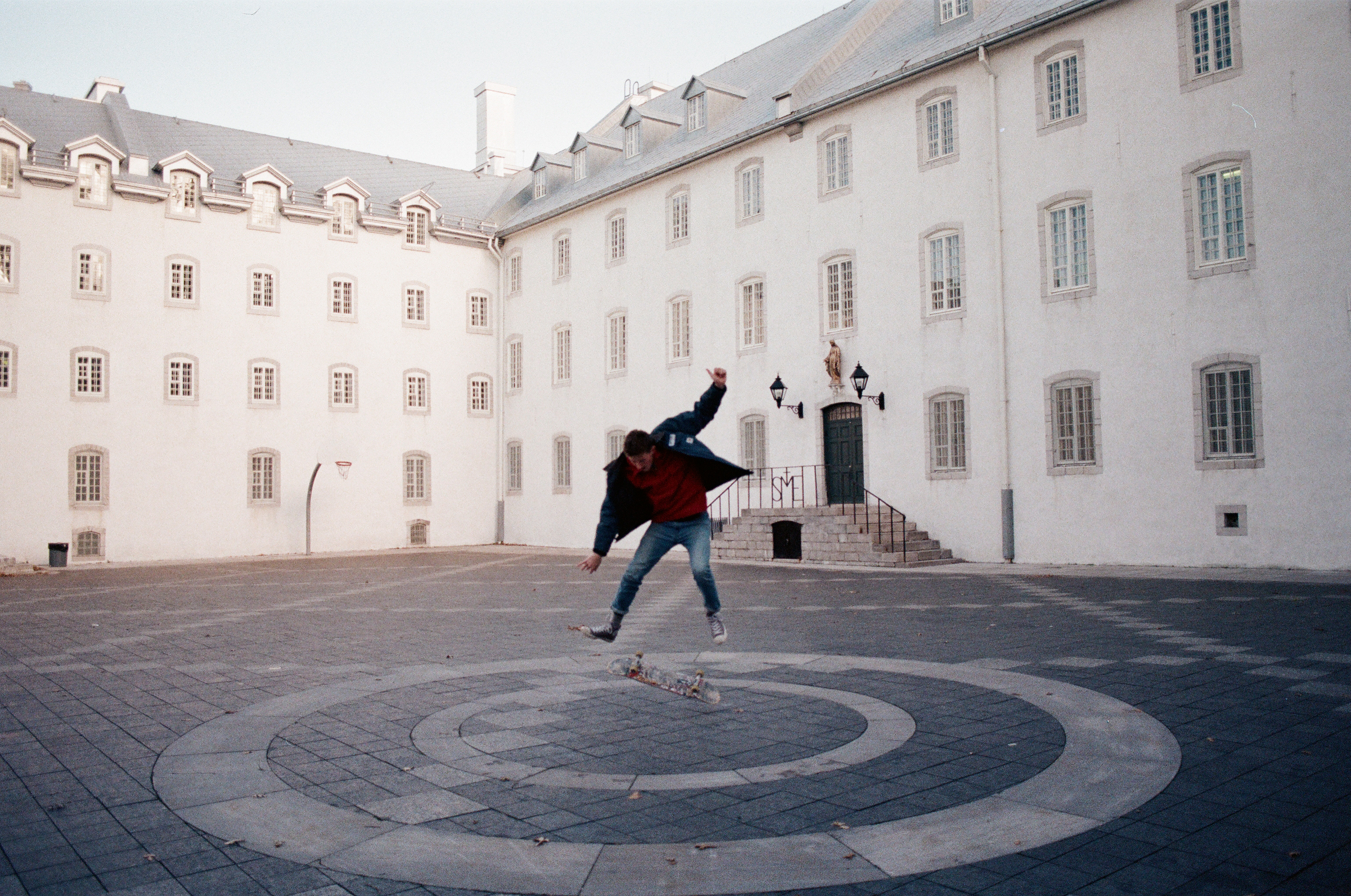 Photo d'un skater réalisant une figure dans la cour de l'École d'architecture de l'Université Laval